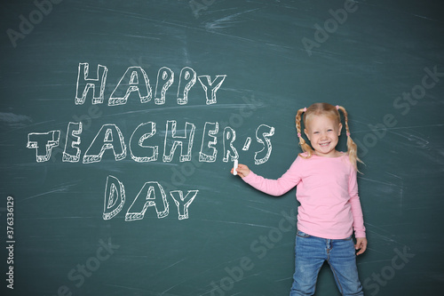 Cute little girl pointing on chalkboard with text Happy Teacher's Day photo