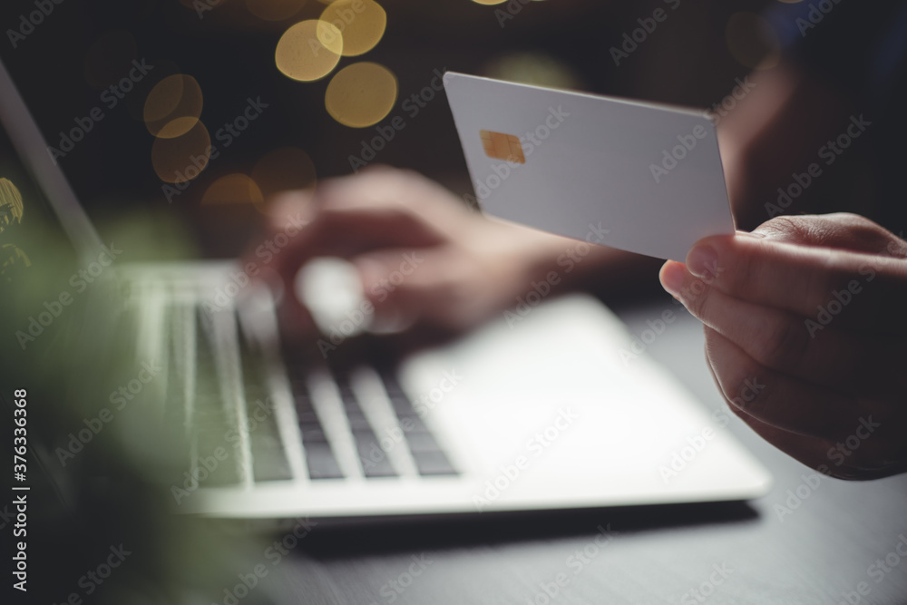 Close up shot of hands holding credit card typing message on laptop for shopping online with glow bokeh background. Close up shot of hands holding credit card typing message on laptop for shopping online with glow bokeh background.