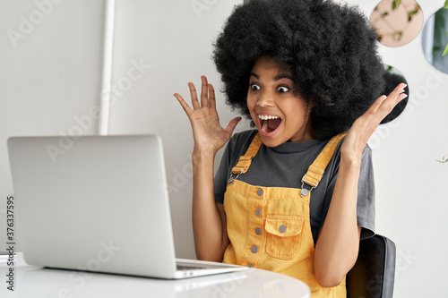 Carta da parati Excited happy hipster African American woman winner, female student looking at laptop laptop feeling amazed looking at computer winning online bid, reading great news, passed exam getting good result