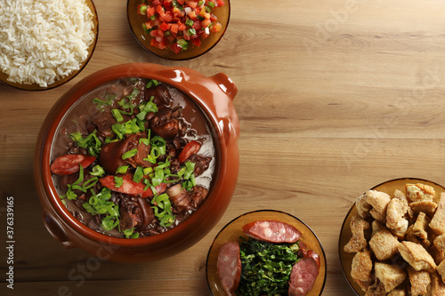 Feijoada, Brazilian food on wooden background. Top view with space for text photo