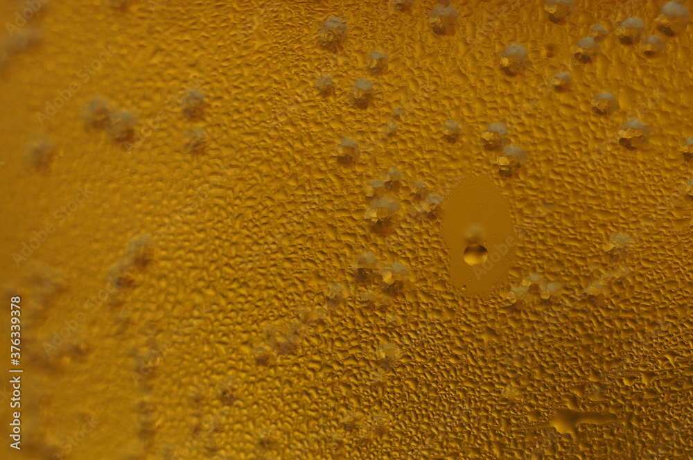Wet glass of beer, golden color in the dark Wet glass of beer, golden color in the dark