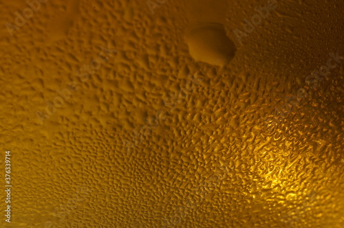 Wet glass of beer, golden color in the dark