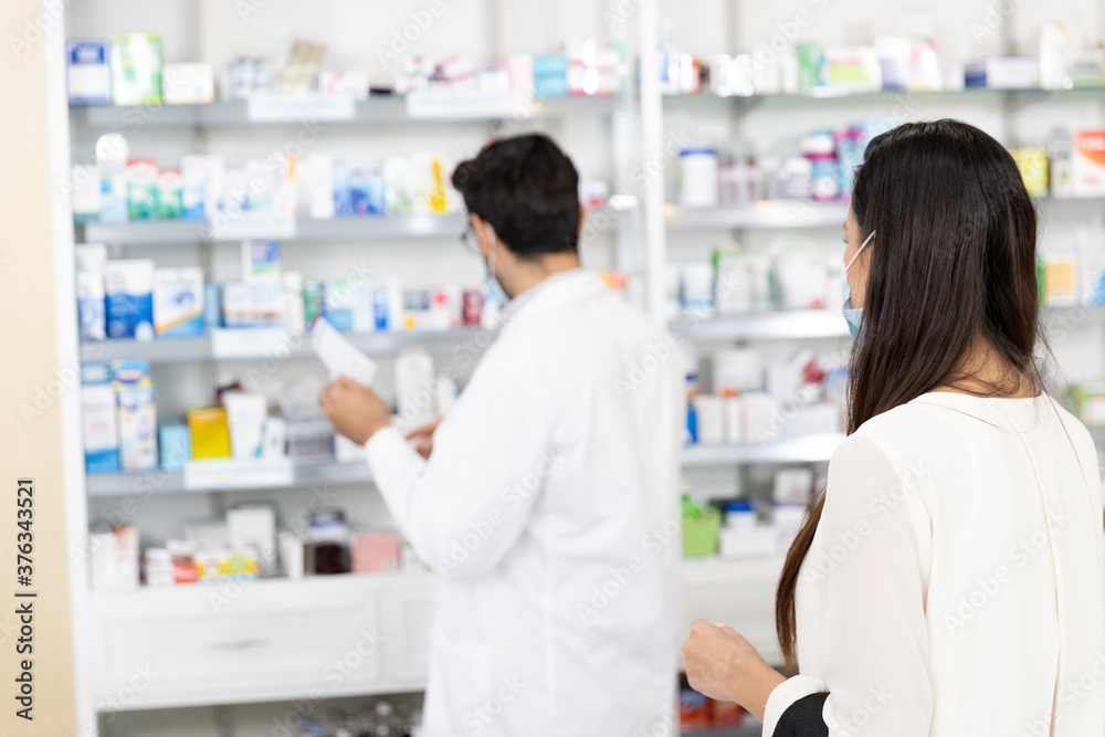 Back view Woman patient and male pharmacist in modern pharmacy. selling medications to prescription