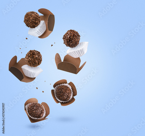 Brigadeiro (Brigadeiro), a Brazilian chocolate candy. Traditional Brazilian handmade chocolate candy. Falling in motion on blue background photo