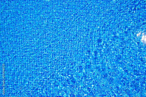 Top view of clear water in a blue tile pool background. Ripple effect