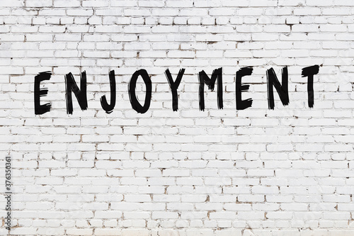 White wall with black paint inscription enjoyment on it