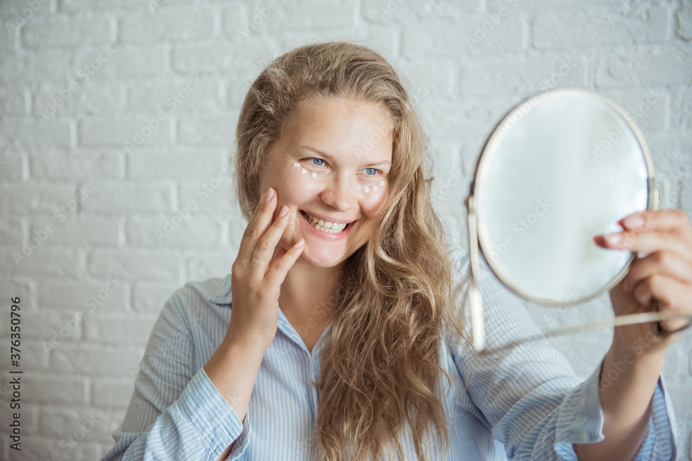 Smiling woman applies cream against wrinkles Smiling woman applies cream against wrinkles