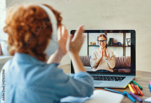 Ginger boy listening to friendly teacher and clap your hands during online lesson photo