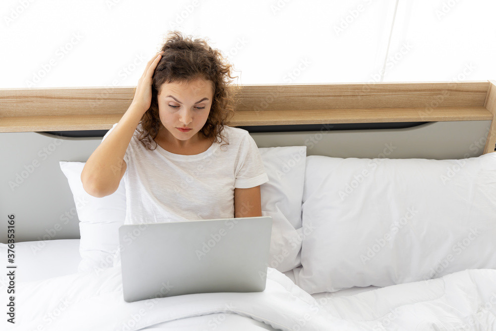 Attractive young woman using computer laptop on the bed. Lifestyle , technology, modern and work from home concept Attractive young woman using computer laptop on the bed. Lifestyle , technology, modern and work from home concept