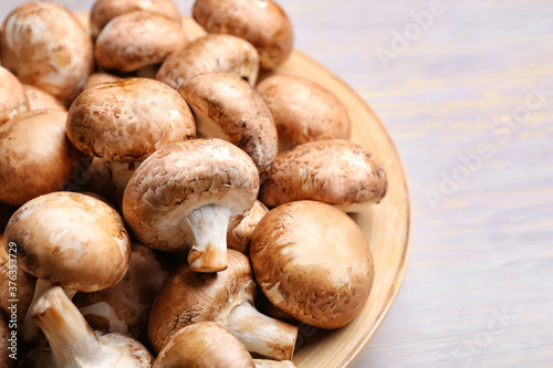 Plate with raw mushrooms on wooden background, closeup