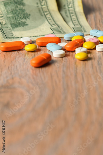 Assorted colored pills and money on the table. The concept of buying pills. The concept of increasing the price of tablets.