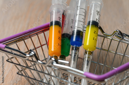The concept of purchasing a covid virus infection medicine vaccine. Colorful syringes in the basket.