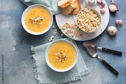 Bowls with tasty popcorn soup on color background