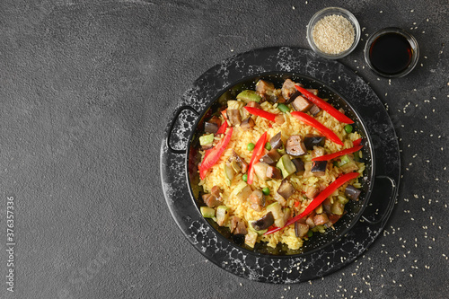 Frying pan with tasty rice on dark background