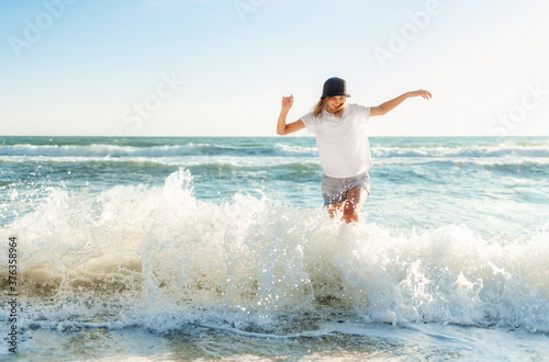 Funny young woman playful on sunset beach. Beautiful happy female on the shore of the blue sea having fun playing splashing water  positive mood  summer vacation  sunny concept
