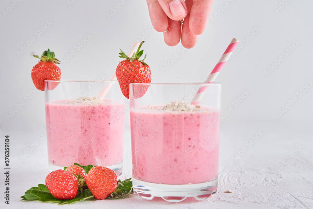 Strawberry milk shake in glass with straw and fresh berries on a white background