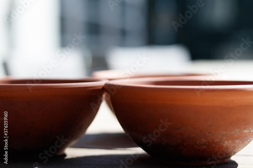 Three terracotta plant pots on a table, casting shadows, with selective focus