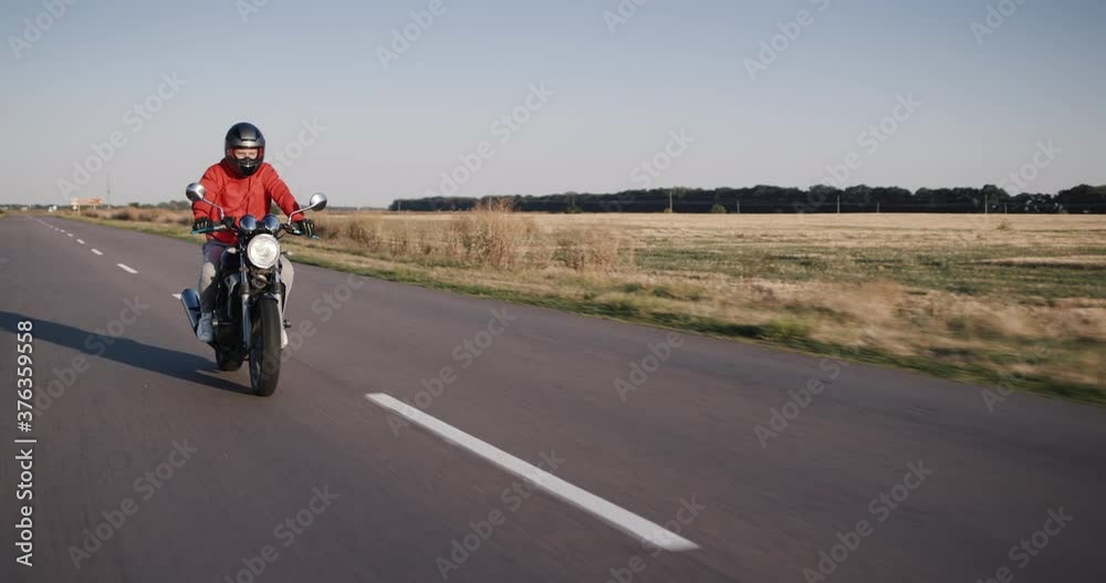 Motorcyclist in a red jacket rides on a country road Motorcyclist in a red jacket rides on a country road