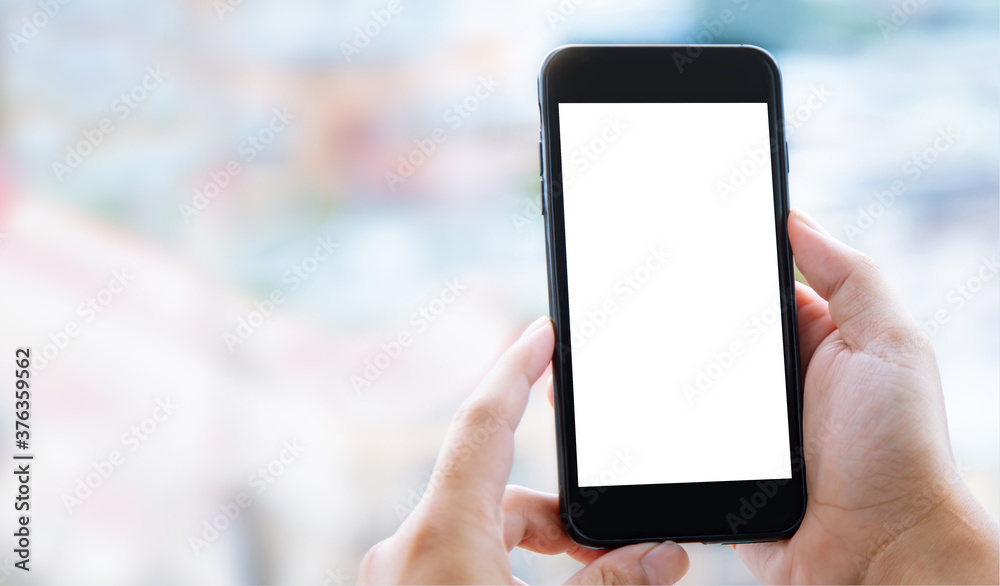 Hands holding mobile phone with blank white screen and copy space on blurred clean background Hands holding mobile phone with blank white screen and copy space on blurred clean background