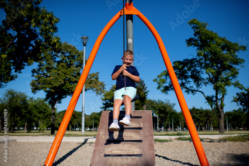 Young boy playing on a zip line at obstacle course in public park during summer day