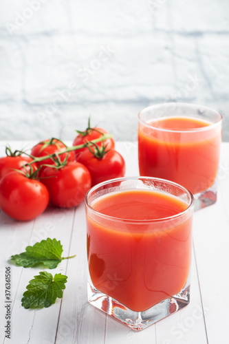 Wallpaper Mural Tomato juice in glass glasses and fresh ripe tomatoes on a branch. White wooden background with copy space. Torontodigital.ca