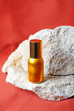 Perfume bottle on a brown or red background and natural stones. Natural ingredients and eco-friendly materials.