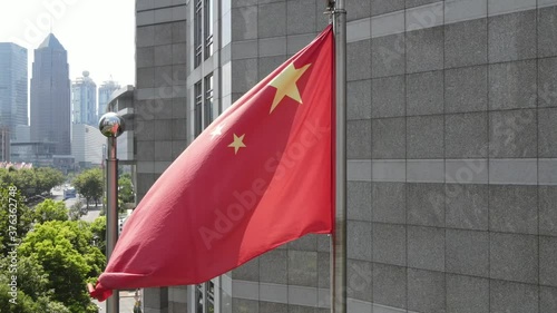 Chinese national flag in Shanghai downtown in sunny day drone aerial view. Red five star flag of China and the downtown aerial view in the background. National flag in the wind Shanghai China