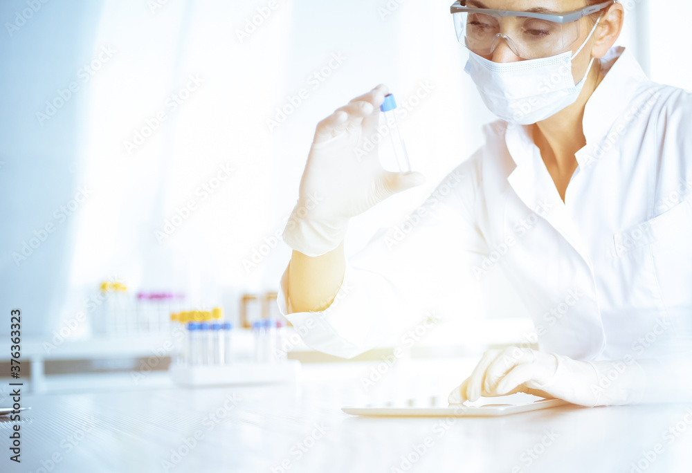 Female laboratory assistant analyzing a blood sample at hospital. Medicine, health care and researching concept Female laboratory assistant analyzing a blood sample at hospital. Medicine, health care and researching concept