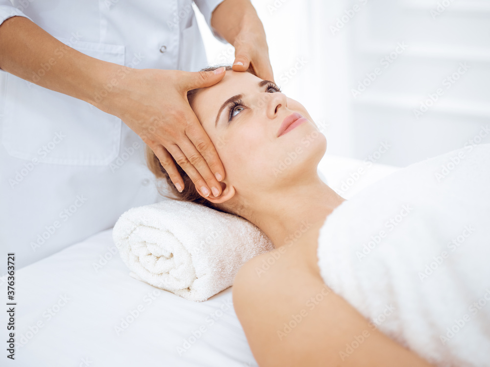 Young and blonde woman enjoying facial massage in spa salon. Beauty concept Young and blonde woman enjoying facial massage in spa salon. Beauty concept
