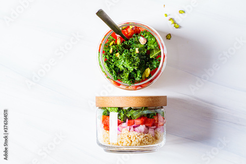 Fotografie Vegan salad with vegetables and quinoa in glass jars, white background, copy space, top view