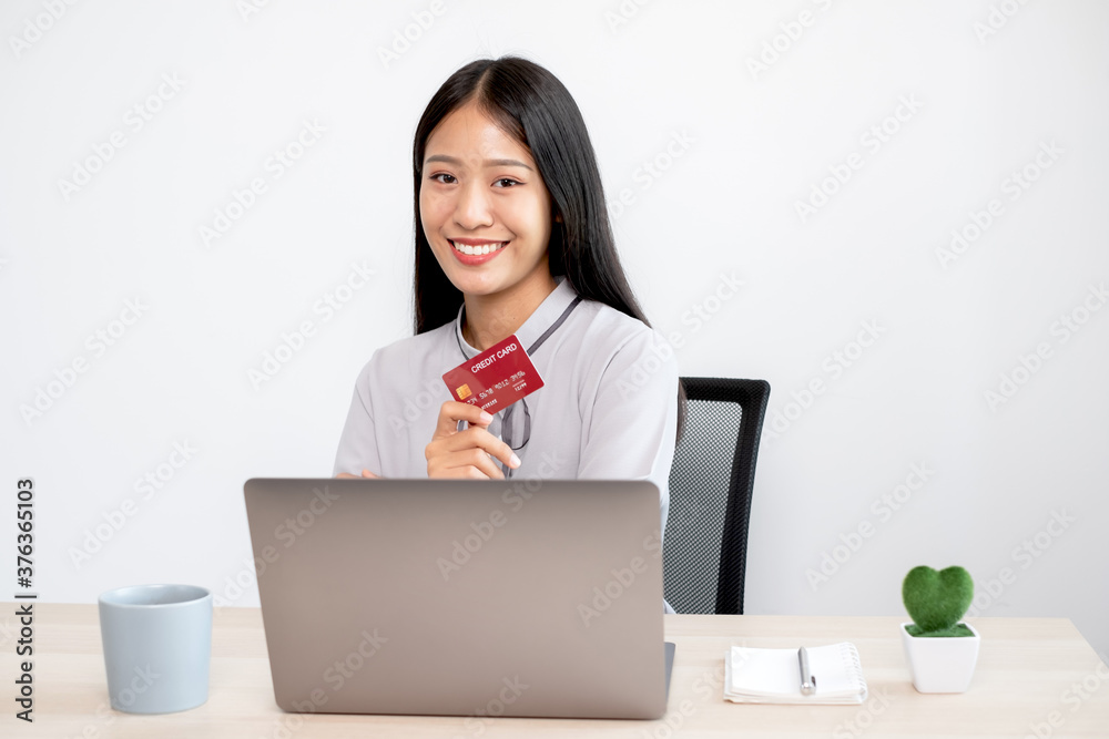 The Asian businesswoman's hand is holding a credit card and using a laptop for online shopping and internet payment in the office The Asian businesswoman's hand is holding a credit card and using a laptop for online shopping and internet payment in the office
