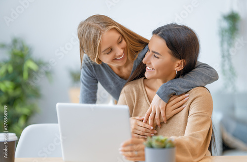 two happy young women using laptop