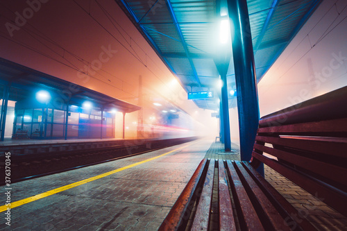 Treno in partenza dalla stazione ferroviaria nella notte nebbiosa photo