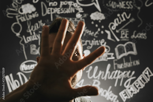 a man in depression close with his hand on the background of a drawn blackboard with problems