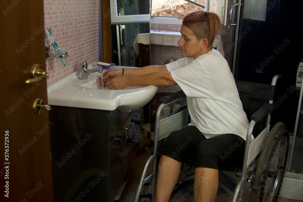 daily life of a disabled person in a wheelchair in the bathroom washing their hands and drying them with a towel viewed from the front daily life of a disabled person in a wheelchair in the bathroom washing their hands and drying them with a towel viewed from the front