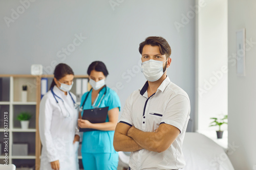Male patient in a medical mask on the background of two female doctors.