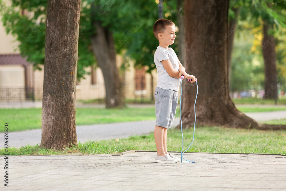 Cute little boy jumping rope outdoors