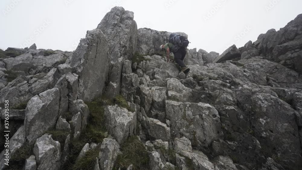 A man climbing down steep mountainside boulders A man climbing down steep mountainside boulders