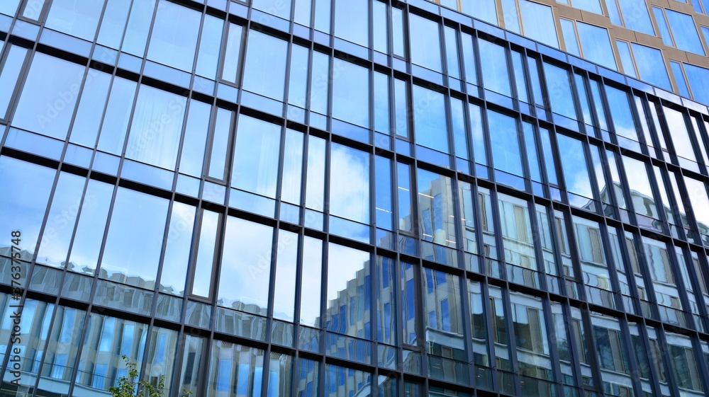 Office building, blue glass wall reflection detail. Modern office building and clear sky background. Office building, blue glass wall reflection detail. Modern office building and clear sky background.