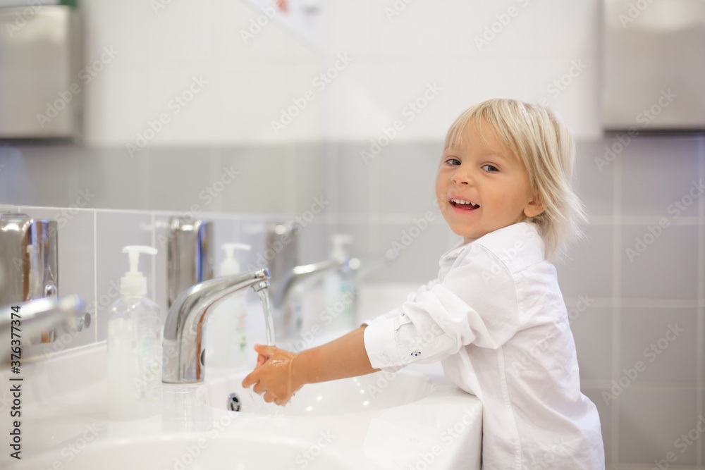 Little preschool child, blond boy, washing hands in bathroom in kindergarden Little preschool child, blond boy, washing hands in bathroom in kindergarden