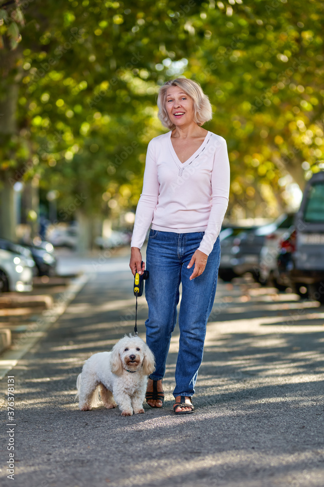 Elderly woman walking with a dog outdoors Elderly woman walking with a dog outdoors