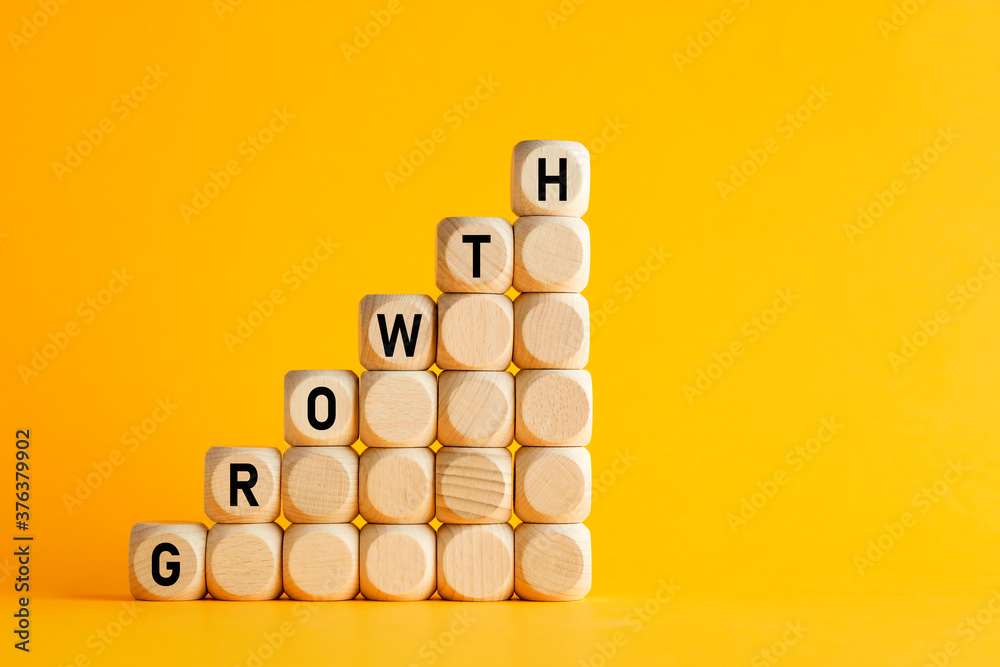 The word growth on stacked wooden cubes against yellow background. Financial or business growth concept. The word growth on stacked wooden cubes against yellow background. Financial or business growth concept.
