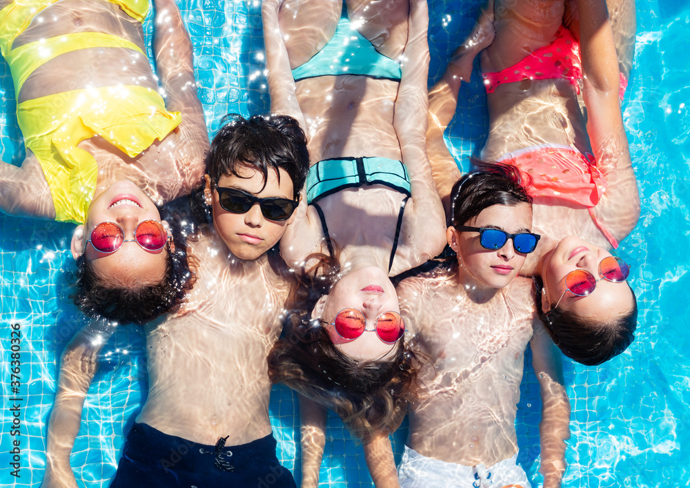 Φωτογραφία Group of children lay in a row in the swimming pool water view from above in sun