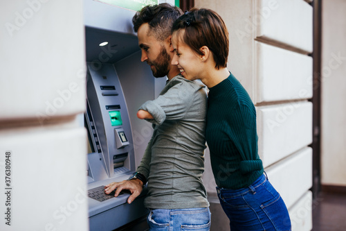 Fotografía Disabled couple usinig ATM machine in city street.