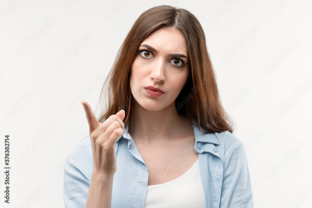 Serious girl with long chestnut hair wagging a finger, scolding somebody. Negative human emotions, body language Serious girl with long chestnut hair wagging a finger, scolding somebody. Negative human emotions, body language