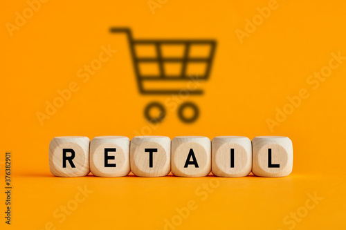 The word retail written on wooden cubes with shopping cart icon on yellow background. Business, sales and marketing concept.