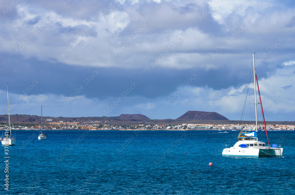 sailboats and catamarans moored in the summer season in Fuerteventura island,in Corralejo, visible in the background