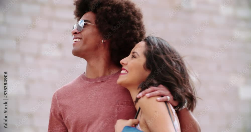 Two people walking together in front of stone wall in sunny day. Man and woman walking and smiling.Romantic couple walking with stone wall in background. Handheld Slow motion Front view focus rack Two people walking together in front of stone wall in sunny day. Man and woman walking and smiling.Romantic couple walking with stone wall in background. Handheld Slow motion Front view focus rack