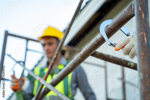 Professional worker wearing safety harness and safety line working on scaffolding at construction site. photo