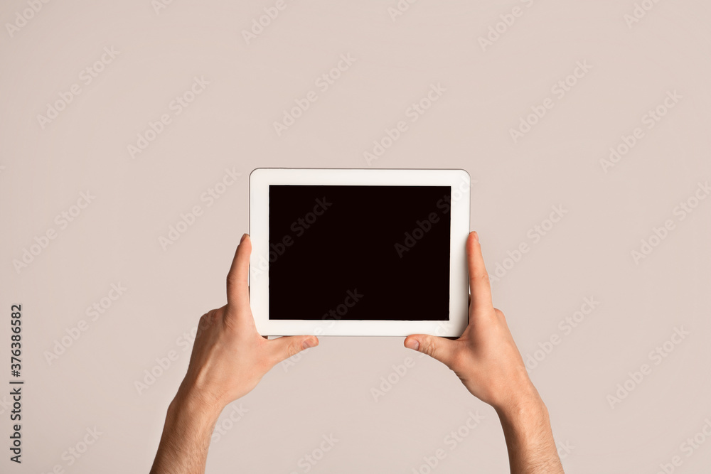 Male hand holding tablet computer on light background, mockup for design
